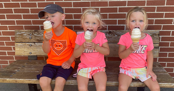 Three kids eating ice cream cones on a bench at the Missouri State Fair